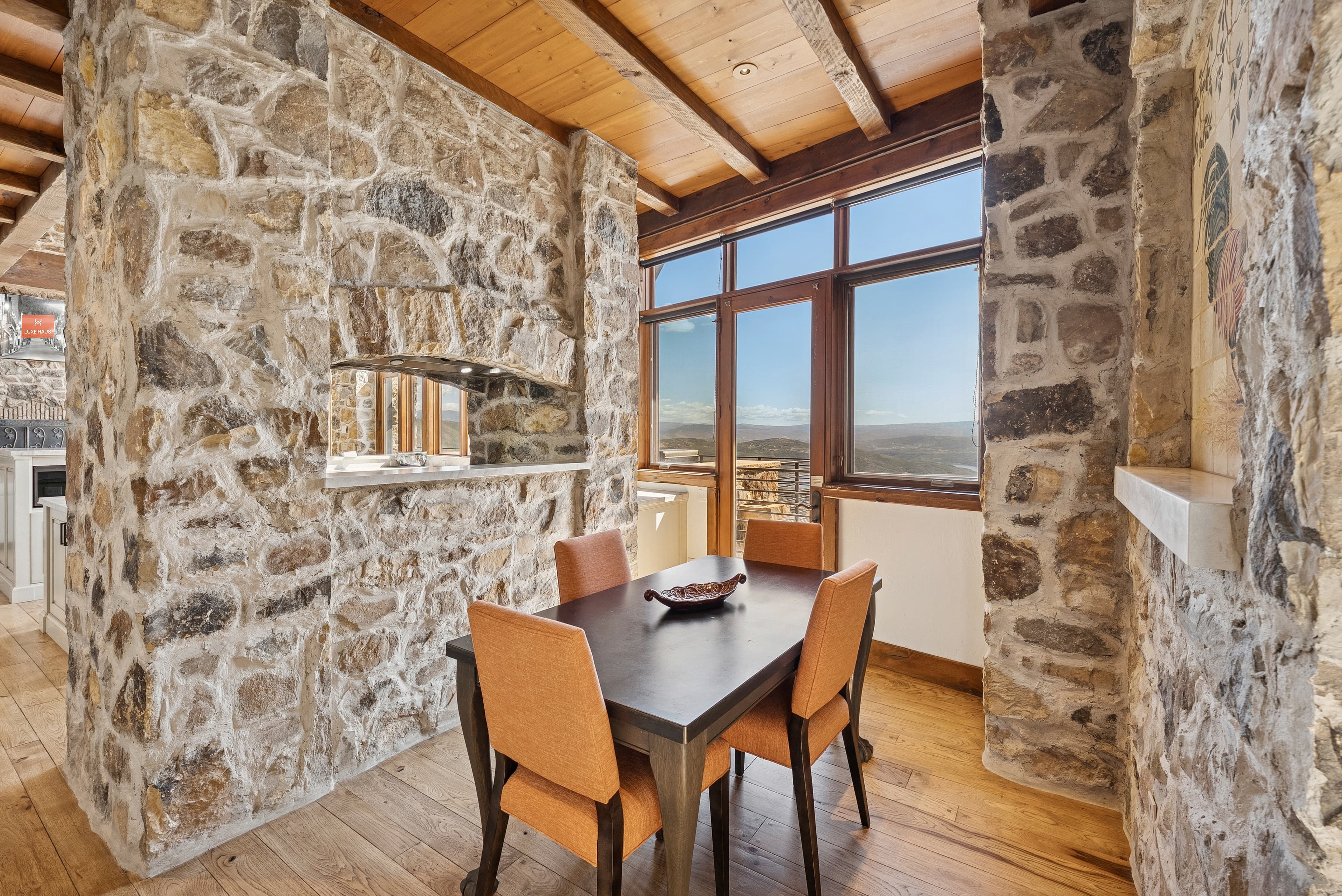 Dining nook with rustic stone walls, table for four, and large windows with views.