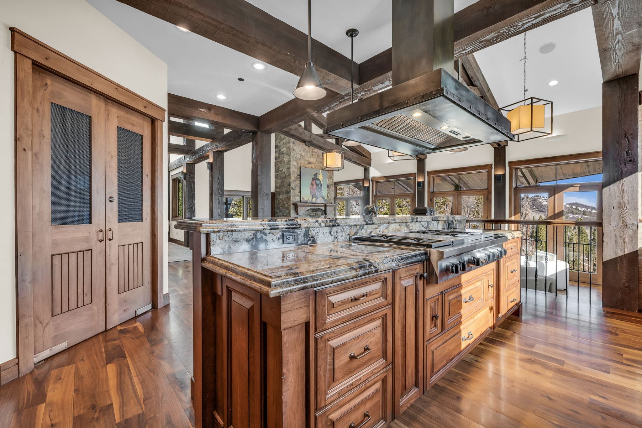 view of kitchen with the living room in the background, there are lots of windows and a luxurious marble countertop